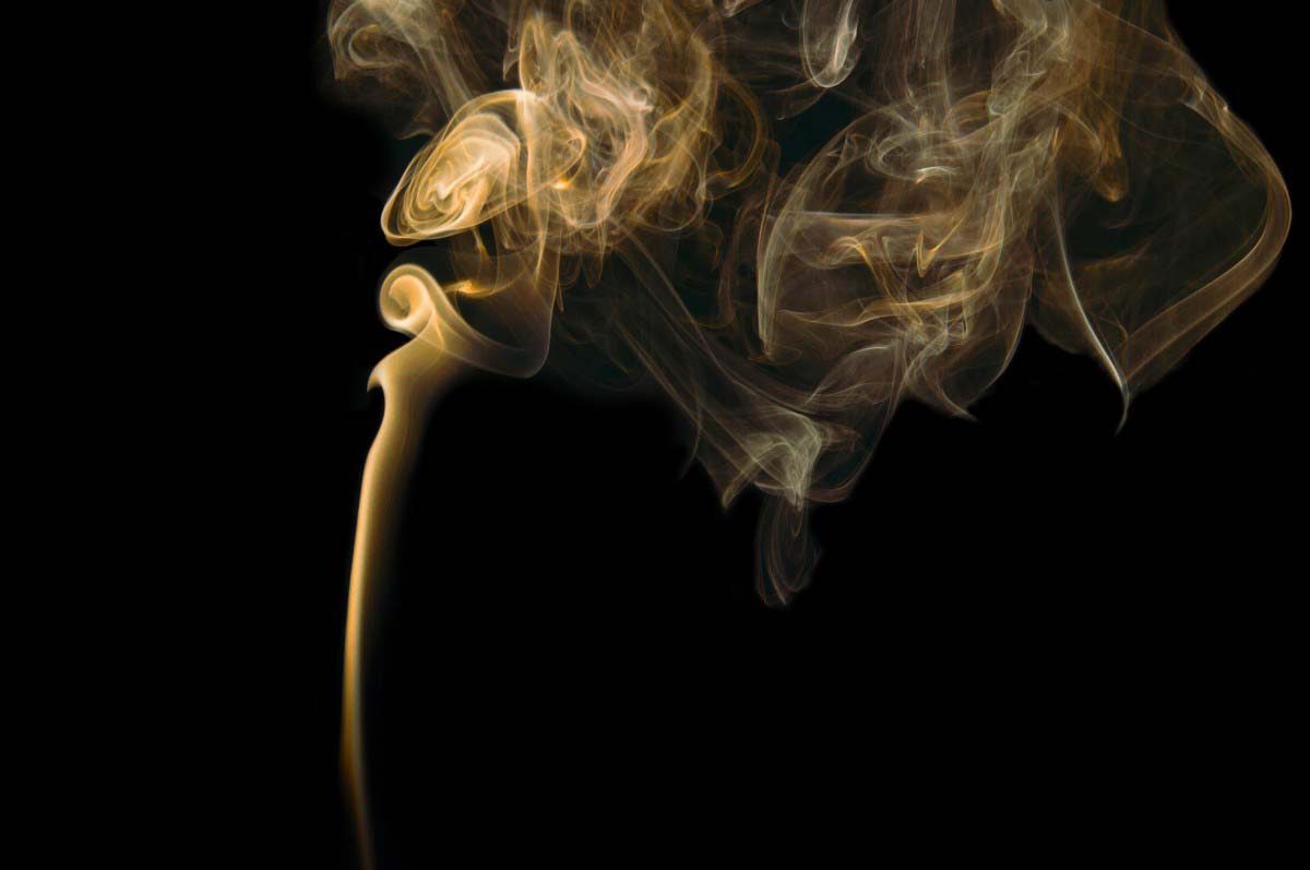A plume of smoke billows into a black screen from an unseen object below.